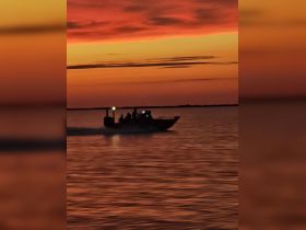 A boat navigates through shimmering waters at sunset, creating a picturesque scene perfect for evening adventures on the water.
