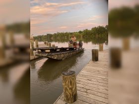 A fisherman navigates his boat towards the dock at sunset, creating a serene atmosphere perfect for evening fishing trips.