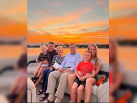A joyful family gathers on a boat at sunset, capturing a memorable moment together — perfect for family outings and celebrations on the water.