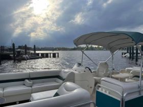 Interior view of a spacious pontoon boat featuring comfortable seating and a helm, perfect for relaxing on the water.