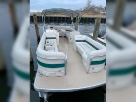 Interior view of a spacious pontoon boat featuring comfortable seating and a shaded area, perfect for relaxing on the water.