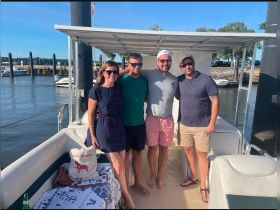 A group of friends poses for a cheerful photo on a boat, enjoying a sunny day on the water — perfect for memorable outings and celebrations.