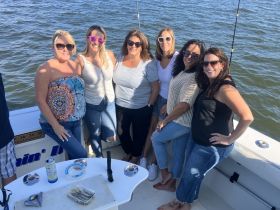 A lively group of friends enjoys a day on the water, posing together on a fishing boat — perfect for creating unforgettable memories on a fun fishing trip.