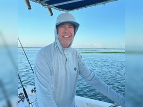A smiling man enjoys a day on the water, showcasing the relaxed atmosphere of boating adventures. Perfect for fishing trips or leisurely cruises.