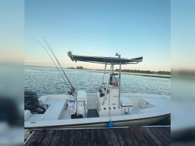 A well-equipped center console fishing boat docked by the water, showcasing its spacious layout and fishing gear — perfect for a day out on the waves.