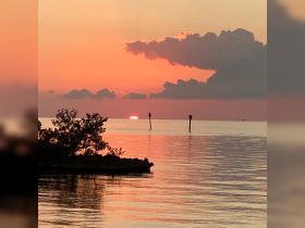 A stunning sunset casts vibrant colors over the water, creating a picturesque coastal scene — perfect for capturing the beauty of nature.