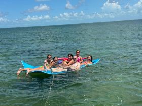A lively group enjoys a sunny day on a floating mat in the water, capturing the essence of summer fun and relaxation.