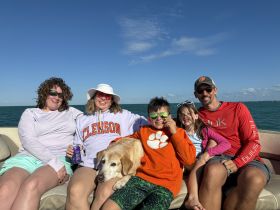 A joyful family enjoys a sunny day on a boat, relaxing together with their dog — perfect for creating lasting memories on the water.