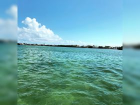 A scenic view of clear turquoise waters under a bright blue sky, showcasing the beauty of a coastal destination.