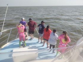 A lively group of friends enjoys a fishing trip on a boat, with excitement in the air as they lean over the side to catch a glimpse of the ocean's bounty.