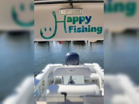 A view of the interior helm area of a boat, featuring comfortable seating and a cheerful 'Happy Fishing' sign, perfect for a day out on the water.