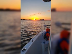 A child enjoys a beautiful sunset view from the boat, creating a serene atmosphere perfect for family outings on the water.