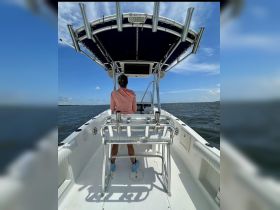 A view of the helm inside a boat, showcasing the console and seating area, with a person at the helm enjoying the open water.