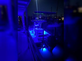 A beautifully lit interior of a boat at night, showcasing the helm and seating area illuminated with blue lights, perfect for evening outings.