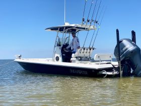 A fisherman stands aboard a Shearwater boat, ready for a day of fishing in calm waters — perfect for outdoor adventures and angling enthusiasts.