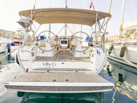 The stern view of the 'Lilly G' yacht docked in a marina, showcasing its elegant design and spacious deck — perfect for sailing adventures.