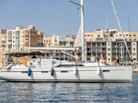 A lively group enjoys a day on a sailboat, with paddleboarding equipment ready for fun on the water — perfect for family outings and adventures.
