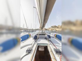 A view of the helm area inside a sailboat, showcasing the seating and cabin space, perfect for relaxing while enjoying the marina scenery.