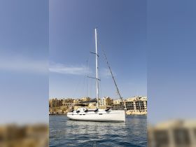 A sleek sailboat docked against a backdrop of coastal buildings, showcasing the perfect setting for sailing adventures.