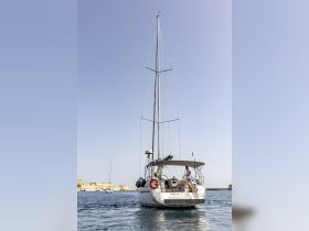 A sailboat named 'Taifun' navigates the waters with a crew member at the helm, showcasing the beauty of sailing adventures.