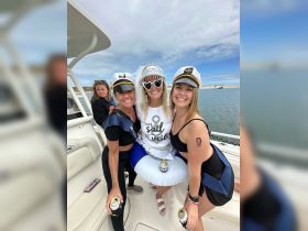 A lively group of friends celebrates a bachelorette party aboard a boat, showcasing fun outfits and drinks — perfect for memorable moments on the water.