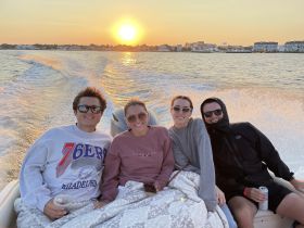 A group of friends enjoys a picturesque sunset while relaxing on a boat, capturing the essence of a perfect evening on the water.