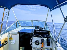 A view of the helm and console inside a boat, showcasing the steering wheel and navigation equipment — perfect for those looking to explore the open waters.