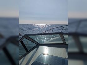 A stunning view from the bow of a boat, capturing the shimmering ocean and a distant vessel, perfect for showcasing the beauty of a day on the water.
