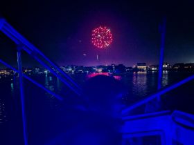 A stunning view of fireworks lighting up the night sky from a boat, creating a festive atmosphere perfect for celebrations on the water.