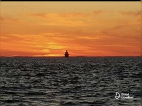 A serene sunset view over the ocean with a silhouette of a boat on the horizon, perfect for capturing the tranquility of maritime adventures.