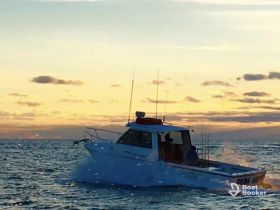 A boat navigates through the water at sunset, creating a picturesque scene perfect for evening excursions and fishing adventures.