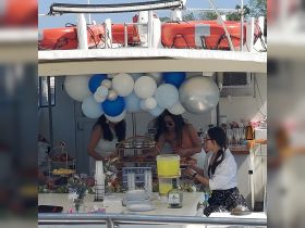 Guests prepare a vibrant spread of food and drinks aboard the boat, perfect for celebrations and gatherings on the water.