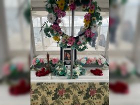 A serene interior setup on a boat featuring a memorial display adorned with flowers and a framed photo, creating a reflective atmosphere for remembrance on the water.