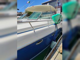 A clear view of a yacht docked at the marina, showcasing its sleek design and structure against a bright blue sky.