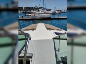 A clear view of the front deck of a yacht docked at the marina, showcasing its spacious layout and inviting sunbathing area.