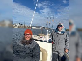Two friends enjoy a day of fishing on their boat, showcasing camaraderie and the thrill of the catch on the water.