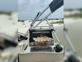 A grill set up on a boat with shrimp skewers cooking, perfect for a delicious onboard barbecue experience.