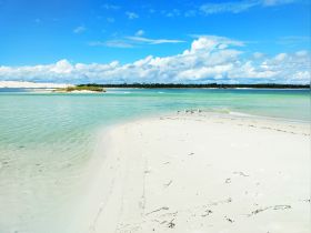 A stunning view of a tranquil beach with turquoise waters and a small island, perfect for showcasing the natural beauty of coastal destinations.