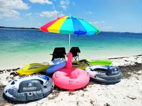 A vibrant setup on the beach featuring colorful inflatables and a sunshade umbrella, perfect for a fun day of relaxation and water activities.