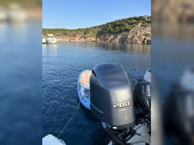 A close-up view of a Yamaha outboard motor on a boat, anchored in a serene bay surrounded by rocky cliffs — perfect for exploring coastal waters.