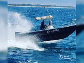 A speedboat named 'Grand Bleu II' cuts through the waves, showcasing an exhilarating ride on the open ocean.