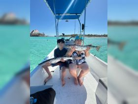 A joyful moment on the water as a woman and a child proudly display their catch while fishing from a boat — a perfect family adventure in the sun.
