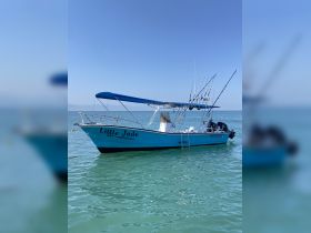 The 'Little Jade' fishing boat is docked in clear turquoise waters, showcasing its sleek design and fishing gear, perfect for a day out on the sea.