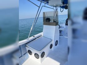 A clean and modern helm area of a boat featuring a seating console and audio speakers, perfect for enjoying time on the water.