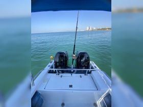 A clear view of the back of a boat with twin engines, set against a tranquil sea and distant skyline, perfect for showcasing vessel features.