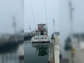 The 'Blue Fin IV' is docked in Montauk, NY, showcasing its classic design amidst a foggy backdrop — perfect for fishing excursions or leisurely cruises.