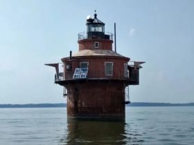 A striking view of a historic lighthouse standing alone in the water, showcasing its unique architecture against a serene backdrop.