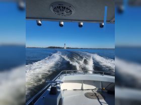 A scenic view from the bow of a boat cruising through calm waters, with a lighthouse visible in the distance — perfect for maritime adventures.