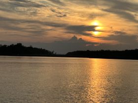 A serene sunset over calm waters, reflecting golden hues — a perfect backdrop for peaceful boating experiences.