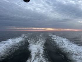 A serene view of the water at sunset, showcasing the gentle waves and a colorful sky — perfect for capturing the tranquility of a boating experience.